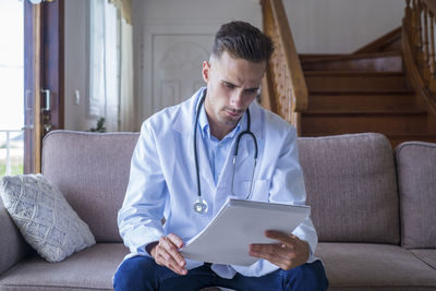 Doctor looking at medical reports while sitting on sofa
