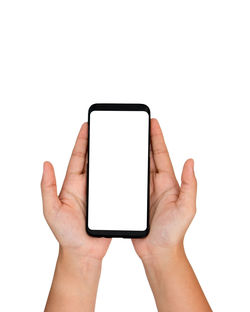 Low section of person holding mobile phone against white background