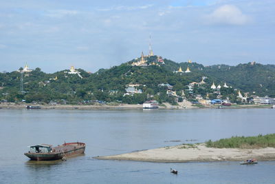 Boats in sea by buildings against sky