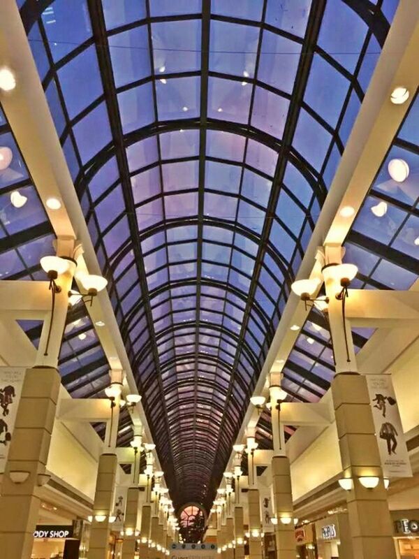 architecture, ceiling, indoors, built structure, low angle view, modern, glass - material, architectural feature, skylight, interior, illuminated, shopping mall, pattern, building, window, travel, no people, building exterior, design, lighting equipment