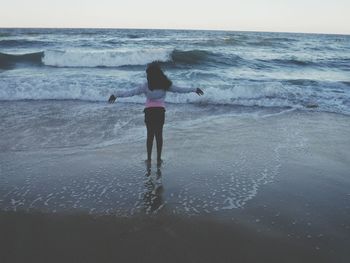 Rear view of woman standing on beach