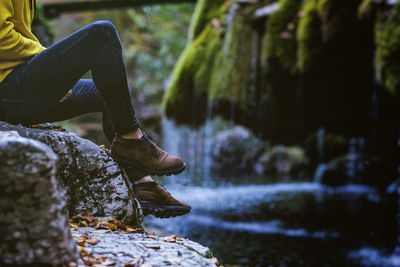 Low section of woman on rock by water