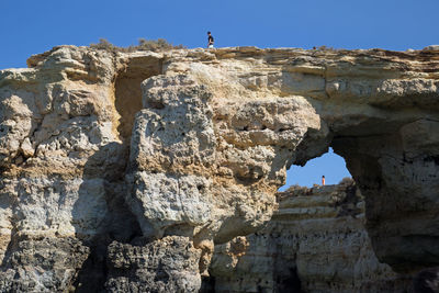 Low angle view of man standing on cliff against clear sky