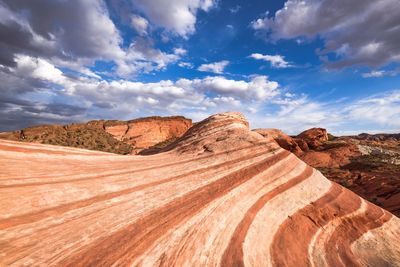 Rock formations in desert against cloudy sky