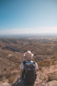 Rear view of man looking at mountains against sky