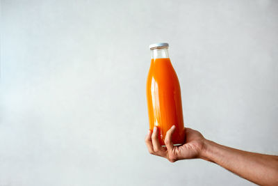 Close-up of hand holding bottle against white background