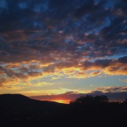 Silhouette of landscape against cloudy sky