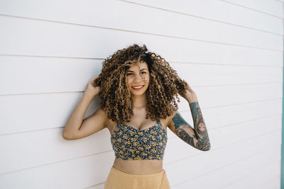 Woman with curly hair standing against wood