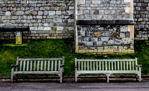 Empty bench against brick wall