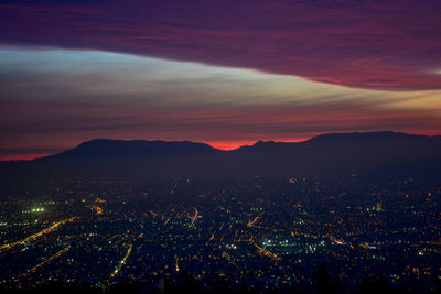 Aerial view of illuminated city against sky at sunset