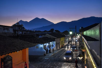 City street and buildings against sky at dusk