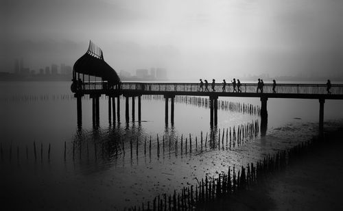 Silhouette of pier on bridge against sky