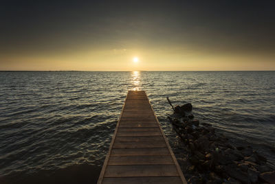 Pier over sea against sky during sunset