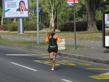 Full length rear view of woman walking on road