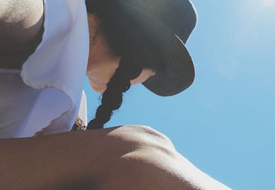 Low angle view of woman sitting against sky on sunny day