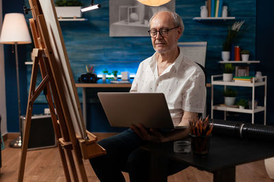Senior man using laptop while sitting at workshop
