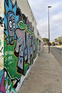 Graffiti on wall by street against sky