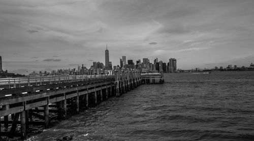 View of buildings by sea against cloudy sky