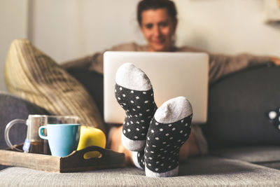 Midsection of woman using laptop while sitting on sofa