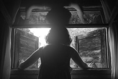 Rear view of girl standing against window