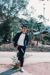 Portrait of young man standing against trees
