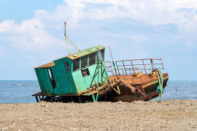 Abandoned boat on beach against sky