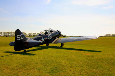 Side view of airplane on field against sky