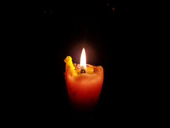 Close-up of lit candle against black background