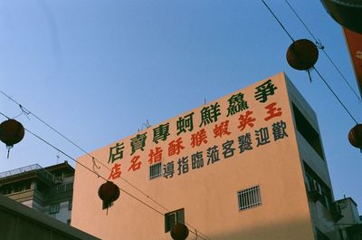 Low angle view of text hanging against clear sky