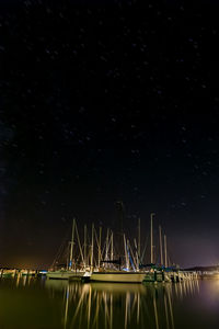 Boats in sea against star field at night