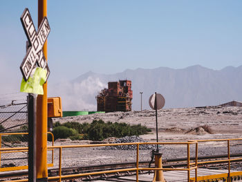 Factory on field against sky seen from railroad station