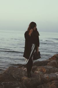 Woman standing on beach against clear sky