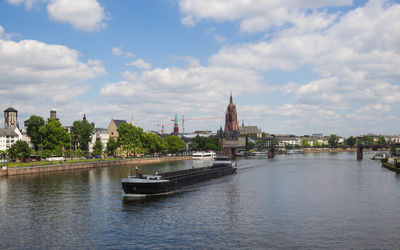 Boat moving on lake against sky in city