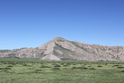 Built structure on field against clear blue sky