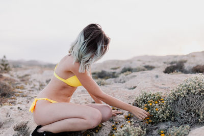 Carefree young woman in yellow bikini on sand at beach