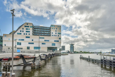 Buildings by river against sky in city