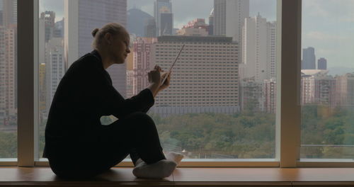 Side view of man looking through window