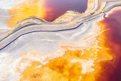 Top view full frame of abstract dried soil textured background with colorful yellow and orange stains creating curved swirls and creative patterns