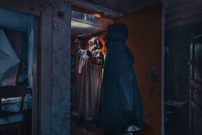 Fictional movie poster. people with flashlights, masks and protective clothing inspect old house. 