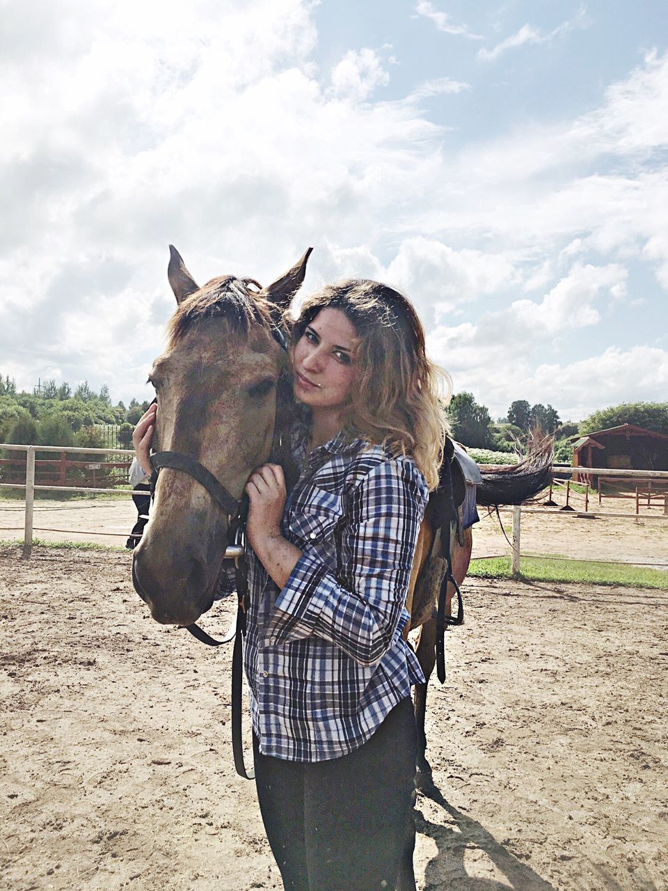 horse, domestic animals, one animal, animal themes, livestock, mammal, leisure activity, casual clothing, day, young women, lifestyles, standing, front view, real people, happiness, young adult, one person, sky, outdoors, bonding, smiling, pets, nature, blond hair, adult, people, adults only
