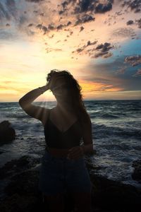 Woman standing at beach during sunset