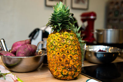 Pineapple on the table with vegetables and kitchen utensils. raw food ingredients for a dinner.