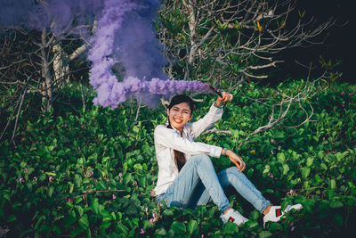 Portrait of smiling young woman sitting on plants