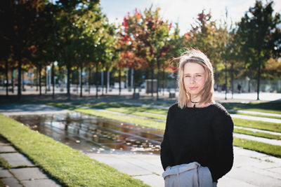 Portrait of young woman standing against trees