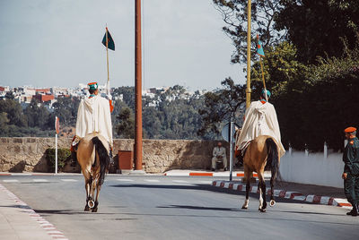 Rear view of man riding horse on street