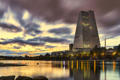 Illuminated buildings against sky at sunset. city of basel, roche towers, switzerland