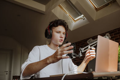 Teenage boy podcasting in front of laptop at home