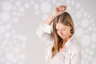 Dreamy woman poses in studio with light light with shadows on white background.