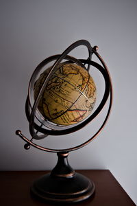 Close-up of globe on table against white wall