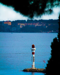 Lighthouse by sea against sky